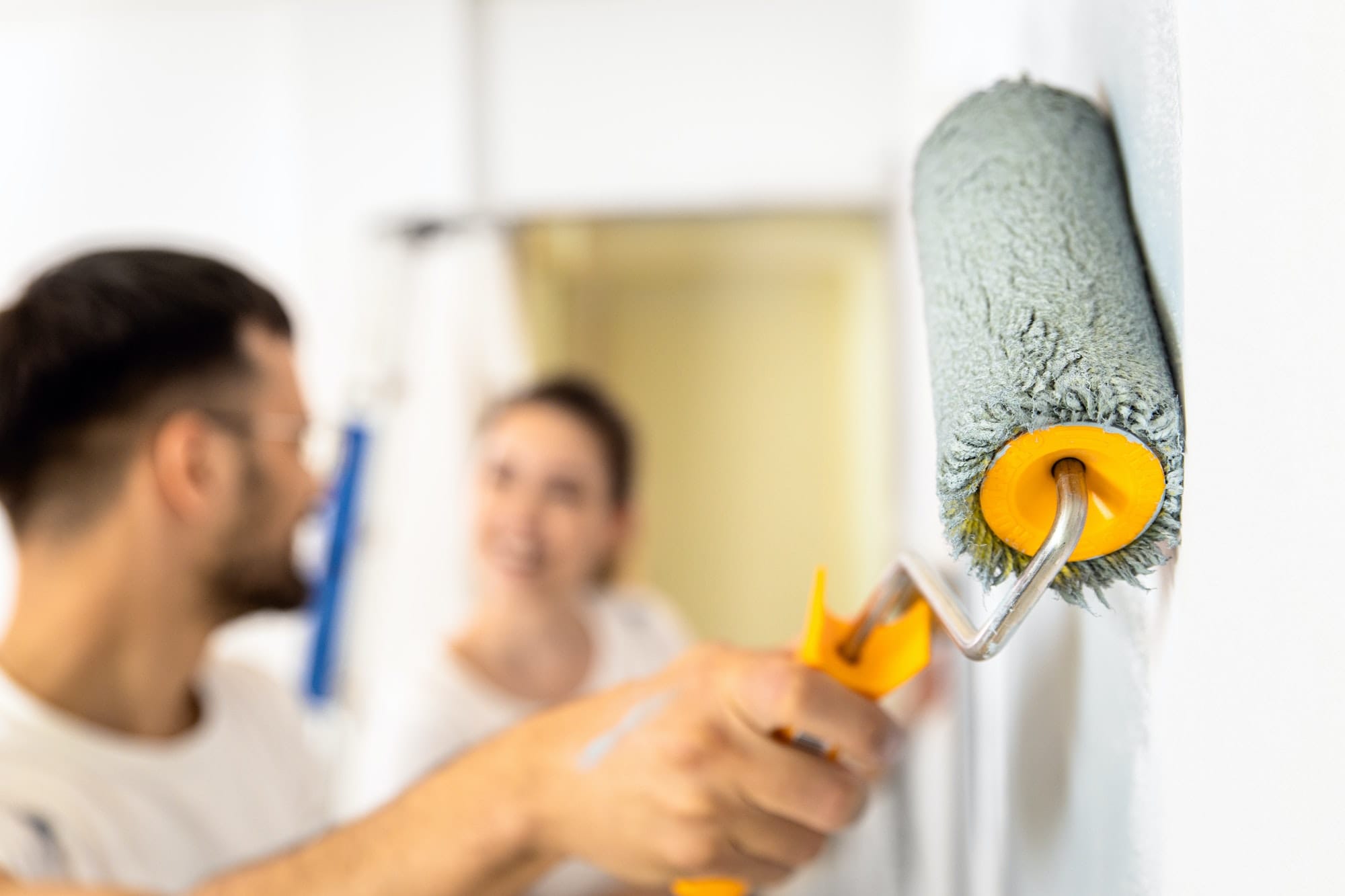 Young couple painting wall in their home.