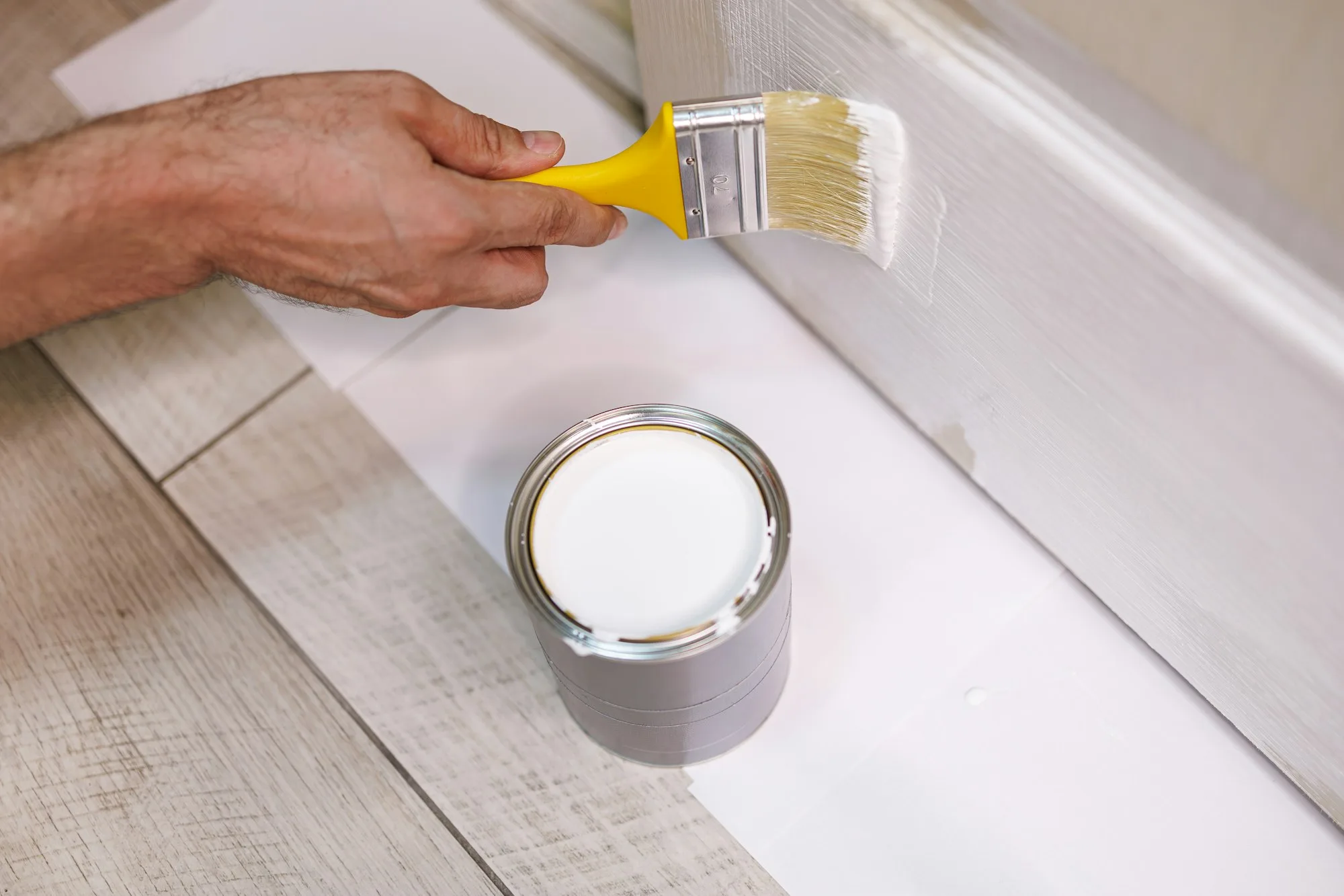 Applying white paint on wood door. Repair staining the doors with paint.